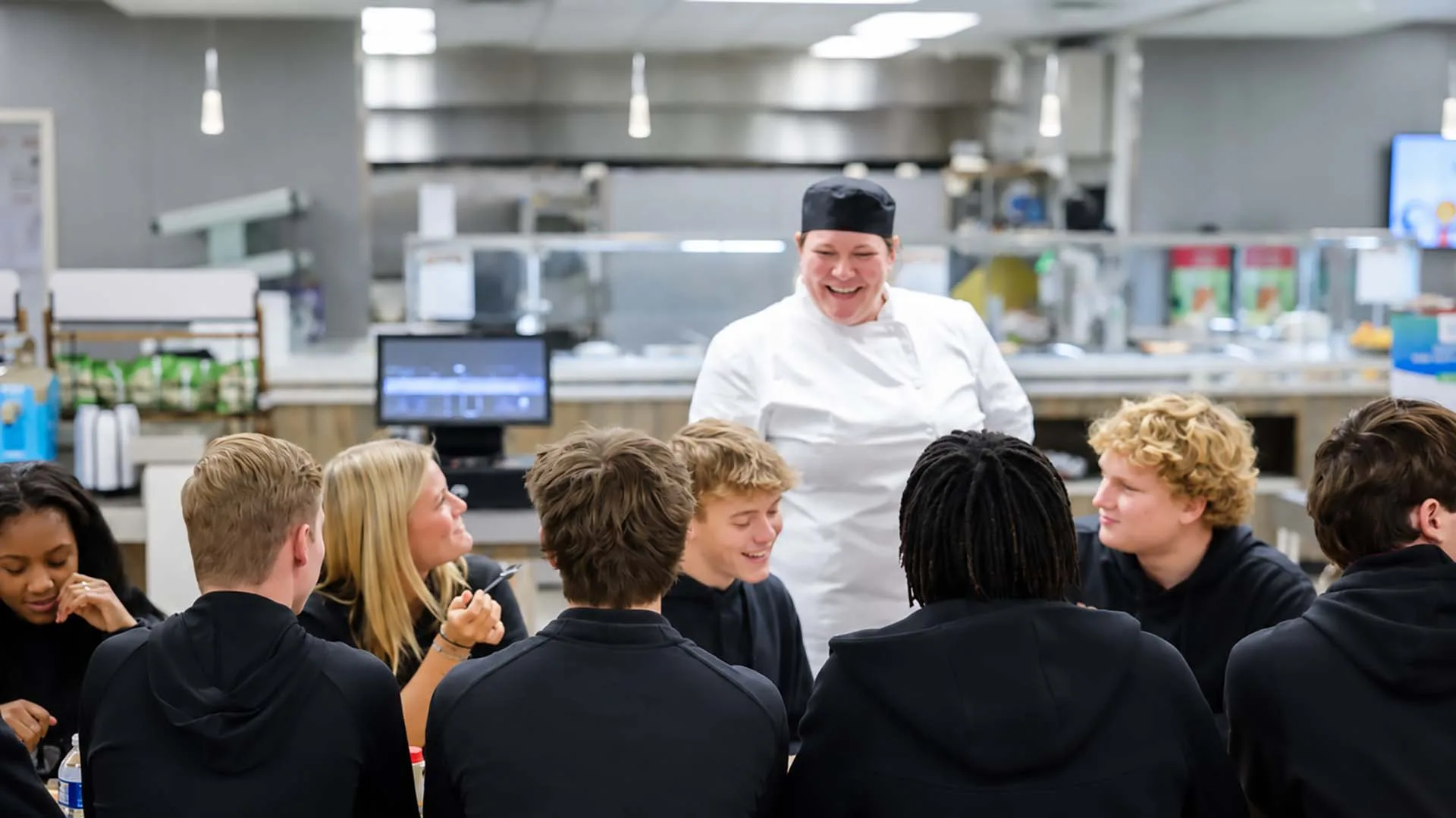 Chef in lunch room talking to table of students