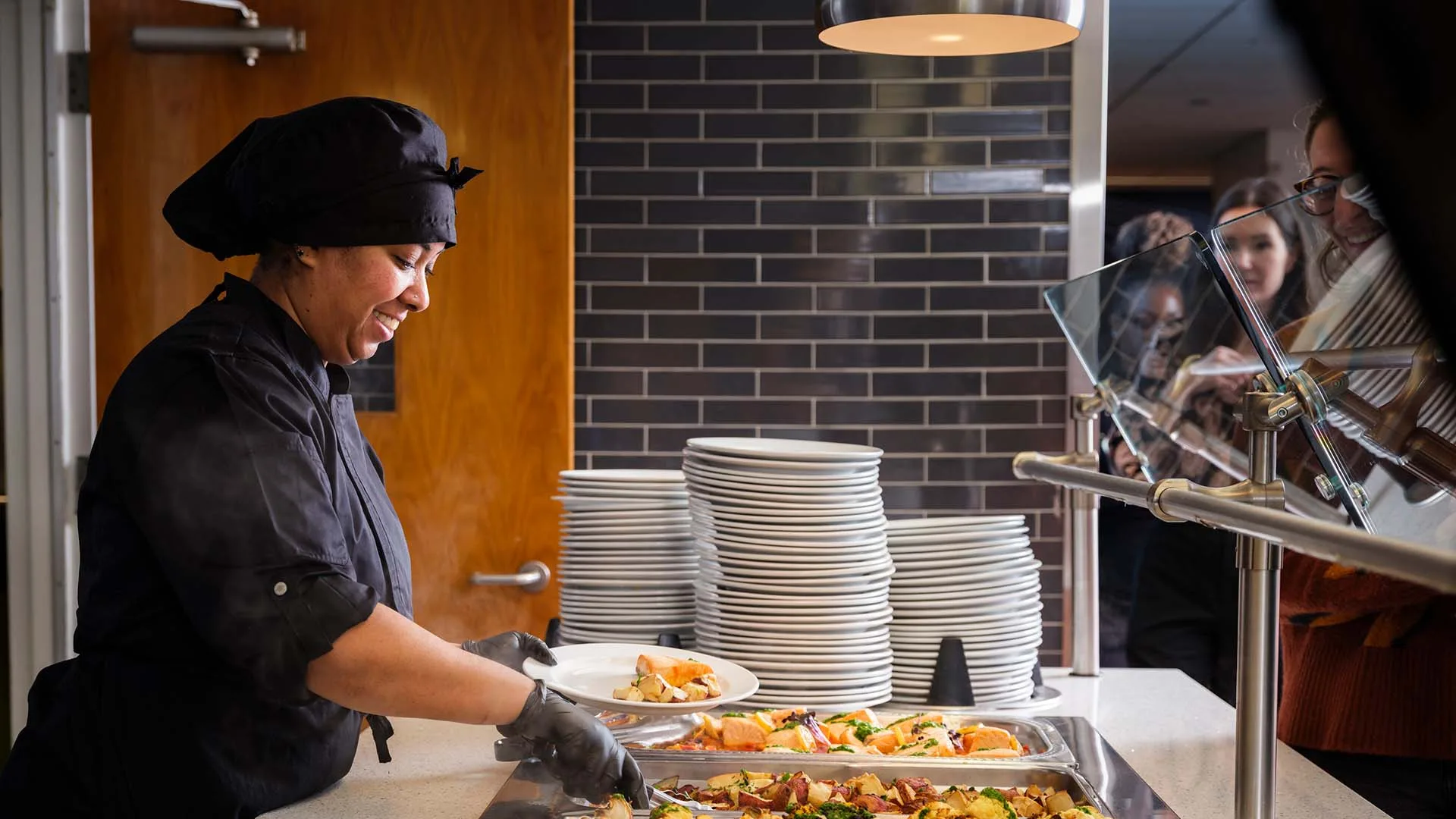Side view of an employee working a serving line with a variety of hot food options